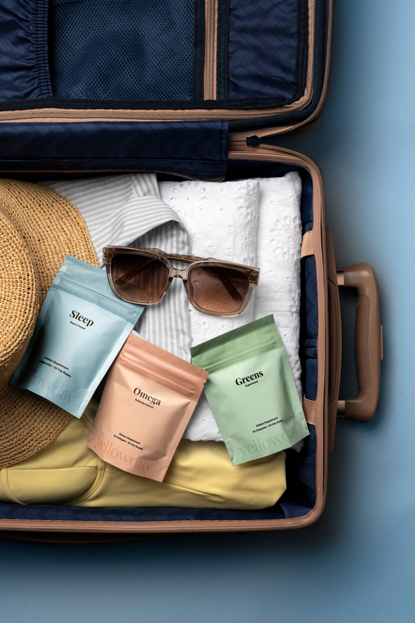 Packed suitcase with Yellowday Sleep, Omega, and Greens supplement pouches